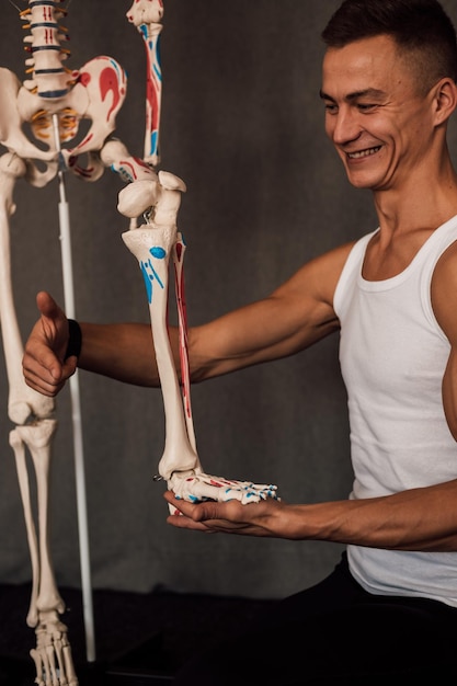 A man holds a skeleton leg in his hands and points a finger at it