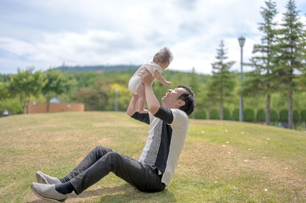 A man holds up a baby in the air, the man is holding him up in the air.