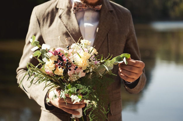 Man holds a wedding bouquet in his hands.Wedding concept.the groom with bouquet.The groom in the suit holds a wedding bouquet. bridal bouquet. The Concept Of Valentine's Day.