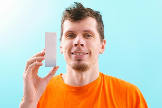 A man holds a white cardboard box template on a blue background. Production