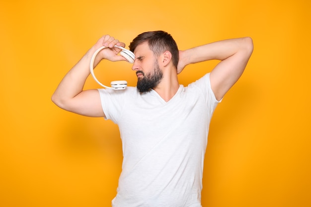 A man holds white headphones in his hand and closed his eyes.