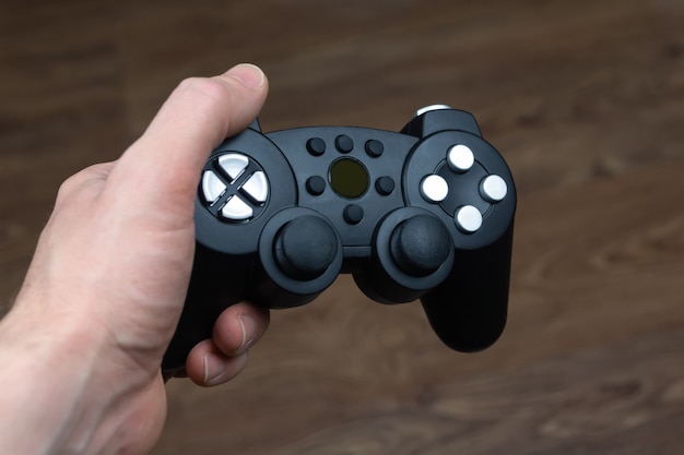 A man holds a wireless gamepad from a video game console in his hand