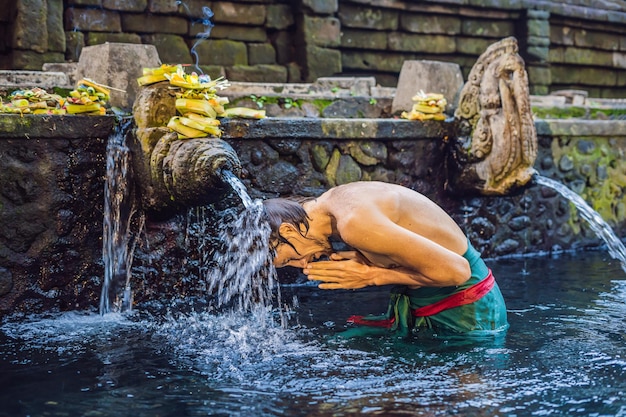 Photo man in holy spring water temple in bali. the temple compound consists of a petirtaan or bathing structure, famous for its holy spring water.