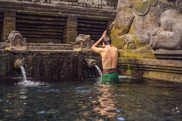 Man in holy spring water temple in bali The temple compound consists of a petirtaan or bathing structure famous for its holy spring water