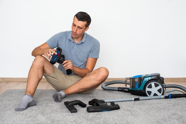 A man at home chooses exactly which brush to attach to the vacuum cleaner