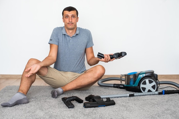 A man at home chooses exactly which brush to attach to the vacuum cleaner