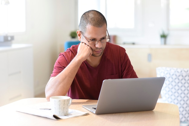 Man at home looking at digital news on laptop