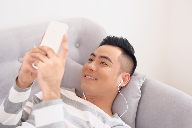 Man at home on sofa listening a music with a smartphone