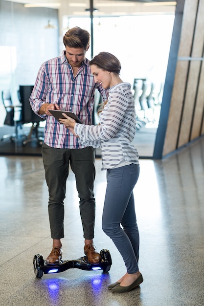 Man on hoverboard using digital tablet with colleagues