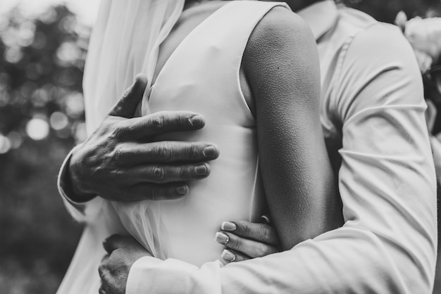 Man hug woman Goosebumps appeared on body of a young beautiful bride from touch man Beautiful skin texture A groom gently embraces girl by shoulders to goosebumps Close up Black and white photo