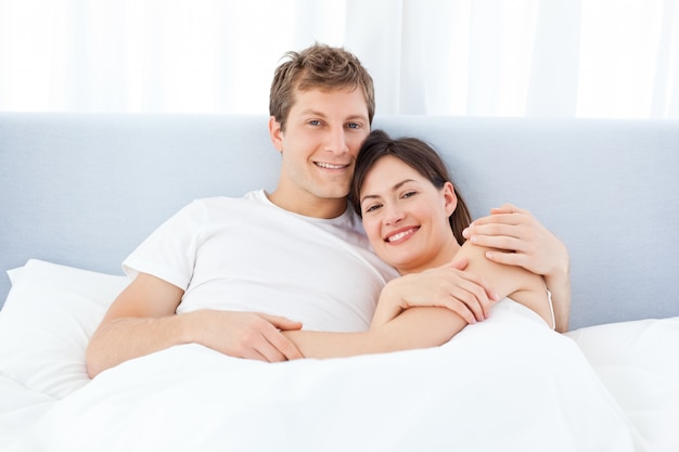 Man hugging his girlfriend on their bed