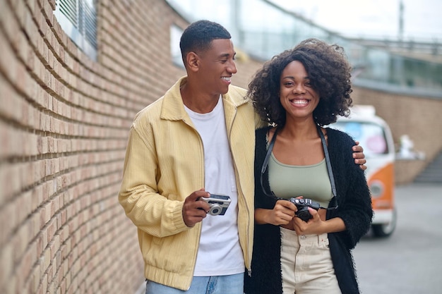 Man hugging woman walking with camera