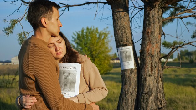 Man hugs girlfriend near poster of missing dog in park