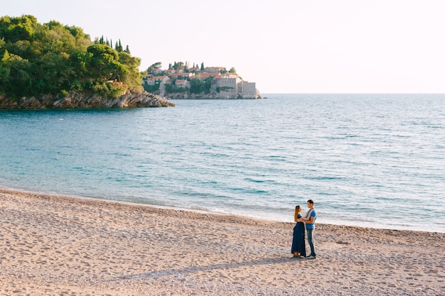 Man hugs woman against the panorama of sveti stefan island and an old villa