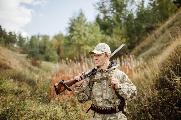 Man hunter with shotgun in forest