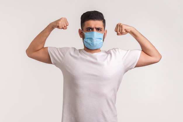 Man in hygienic mask showing strength and immunity to recover from contagious disease