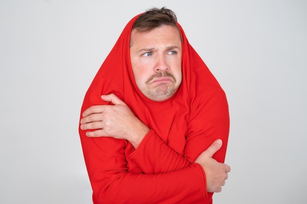 Man ihiding pulling sweater on head in displeasure keeps arms folded