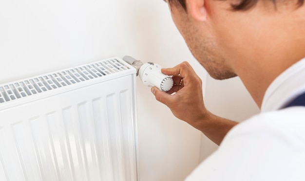 Man increase temperature of radiator by adjusting thermostat