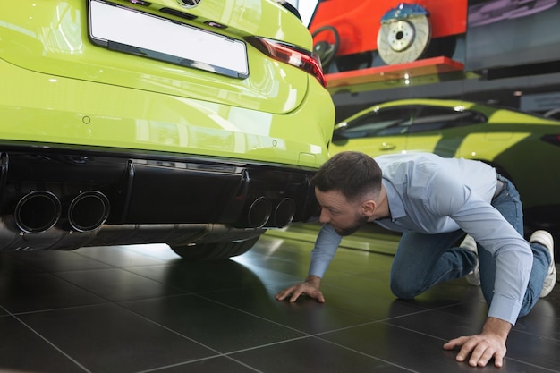 A man inspecting a newly bought new car in a car dealership