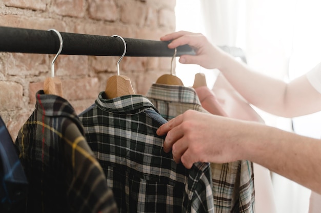 Man is browsing through various shirts hanging on the clothing rack in the wardrobe