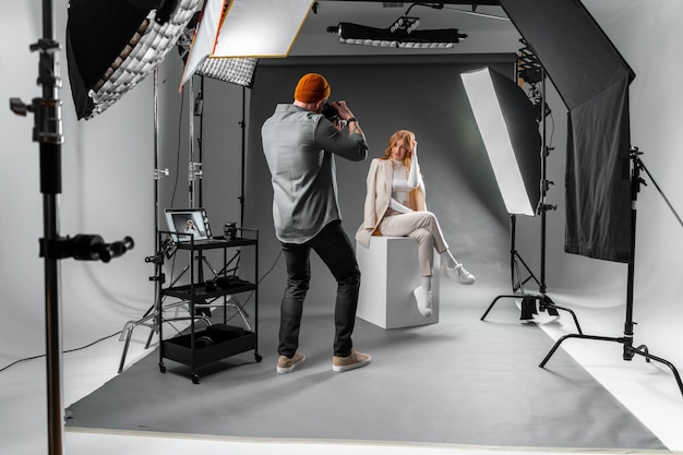 A man is capturing a woman posing on a cube at a photo studio building celebrating an event with