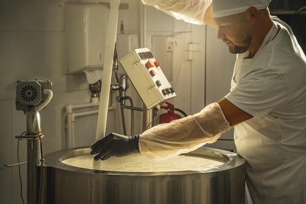 Man is a cheese maker in the process of producing different varieties of cheese in the industry Milk cheese making