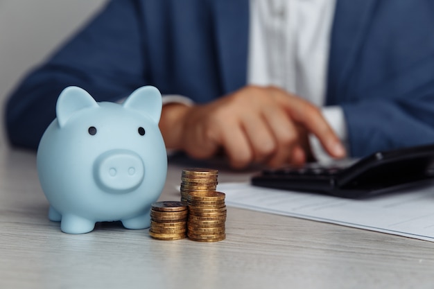 Man is counting profit on a calculator blue piggy bank