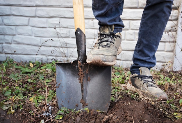 The man is digging the soil ground on his country house