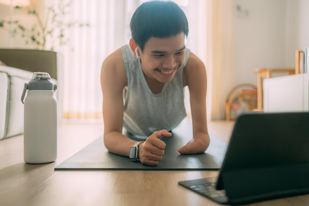 a man is doing push ups on a mat with a laptop disabled young boy doing push ups with laptop water