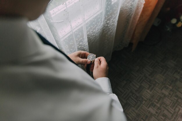 Photo a man is getting ready for a wedding and is adjusting his tie