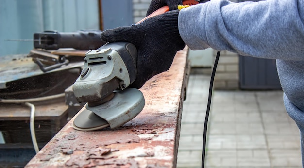 A man is grinding a board Removing old paint from boards Carpentry work