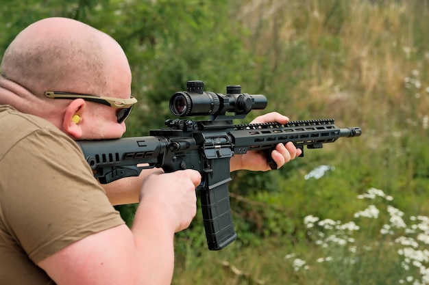 A man is holding an automatic weapon a man looks into the sight of a military weapon