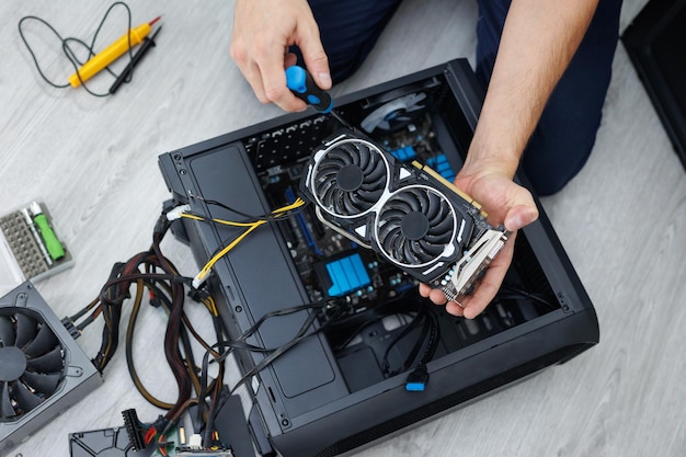 Man is holding a computer video card in his hands Computer maintenance