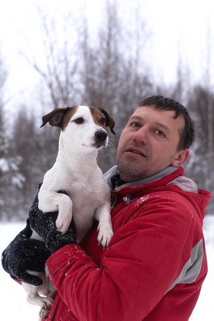 A man is holding a dog in his arms A thoroughbred dog Jack Russell terrier