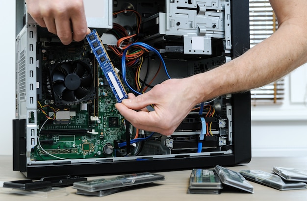 A man is holding a RAM slot to upgrade of the computer.