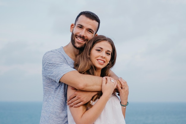 A man is hugging his girlfriend in the highland park near the sea in Spain