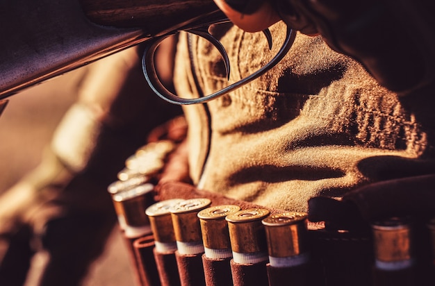 The man is on the hunt. Ammunition bullet. Male hunter ready to hunt with hunting rifle. Close up ammunition. Ammunition with a gun, cartridges. Hunter man. Man is charging a hunting rifle.