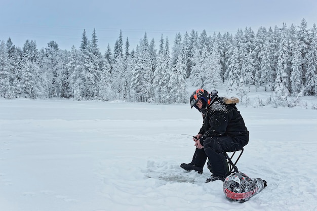 Man is ice-fishing in Ruka in Lapland, Finland