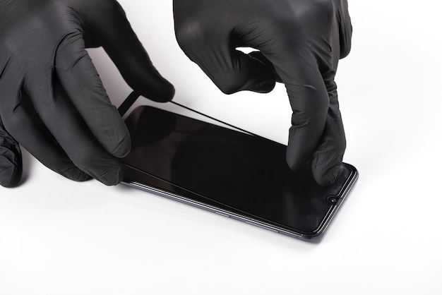 A man is installing a protective glass on the screen of a smartphone.