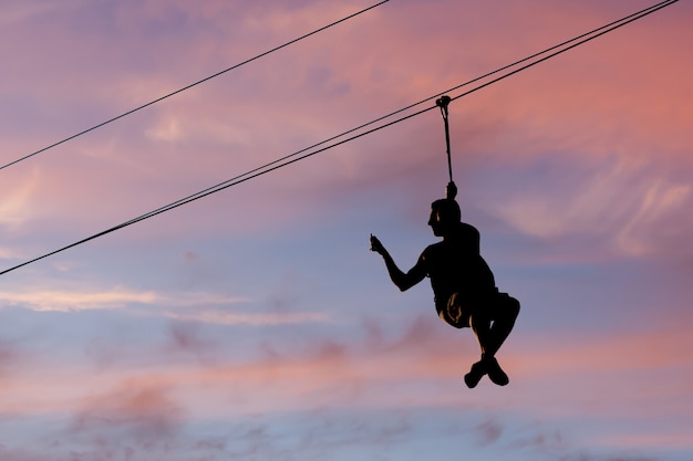 Photo a man is jumping on a rope swing and removing video on the smartphone at the same time