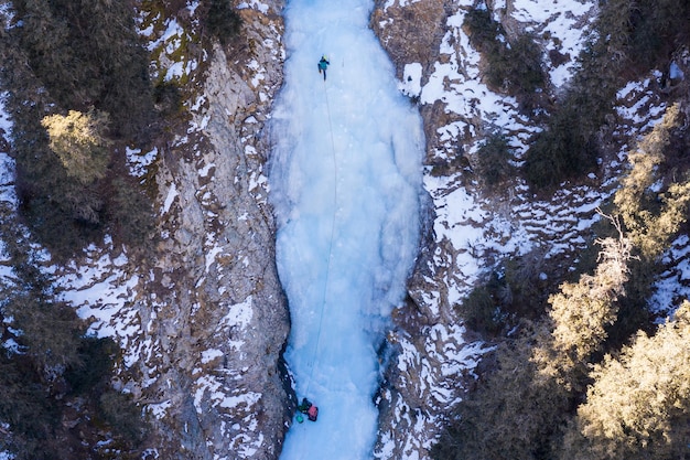 Man is leading on Ice Ice Climbing on Frozen Waterfall Aerial TopDown View Barskoon Valley Kyrgyzstan