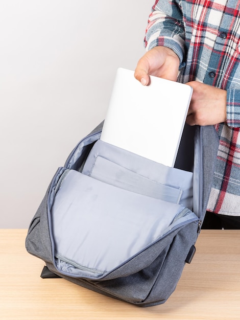 A man is packing his laptop into a backpack closeup