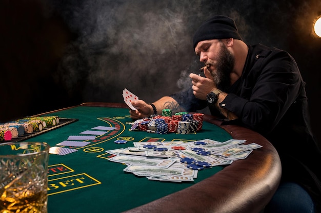 Man is playing poker with a cigar and a whiskey. A man winning all the chips on the table with thick cigarette smoke.