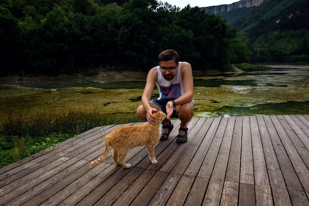 A man is playing with a domestic red tabby cat