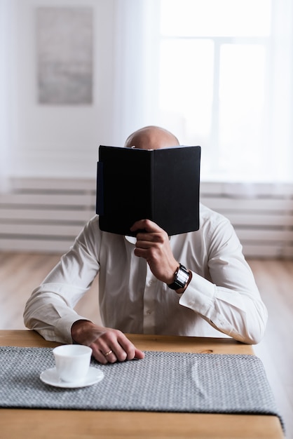 A man is reading something in a black notebook. The concept of freelance, work in the office