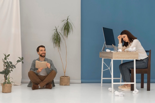 Man is reading while woman working on computer