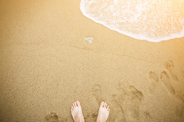 Man is relaxing barefoot at the beach Guy's legs on the sand Waves at the ocean side Summer vacation Travel concept