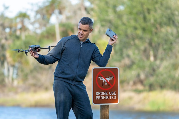 Man is sad that he is not allowed to fly his quadcopter state park no drone area Operator is unauthorised to use UAS near restriction sign