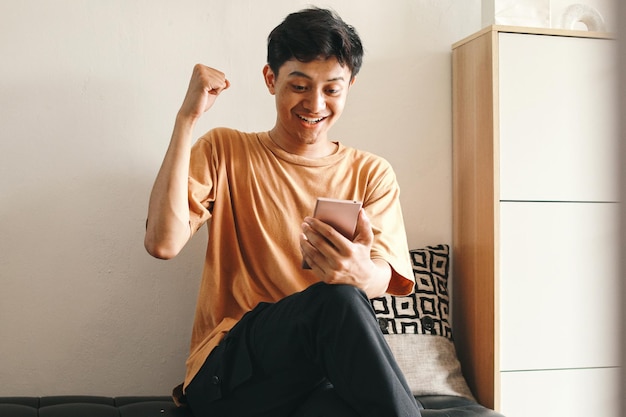 a man is sitting on a couch and smiling with his fist in his hand