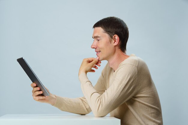 Man is sitting at table and using tablet computer for communication in chat or video chat Social media concept